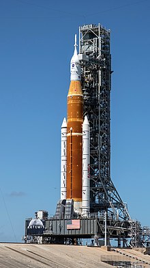 A launch vehicle beside a tower on pad