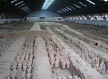 Photographie des soldats de l'armée en terre cuite dans une fosse couverte d'un hangar immense.