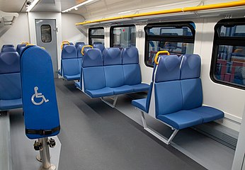 Салон с синими сиденьями и спинками для инвалидов, за которыми видно два дополнительных сиденья