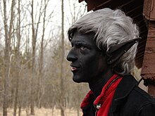 A person dressed as a drow, including black makeup, white hair, and pointed ears