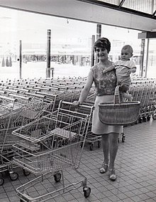 Photographie en noir et blanc d'une femme et son enfant poussant un caddie.