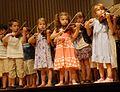 Niños tocando el violín en un recital grupal