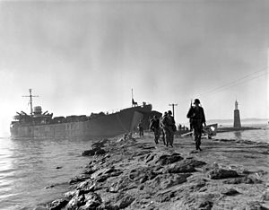 Men disembark from a ship docked on a rocky harbor