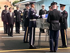 A delegation of United Nations Command Military Armistice Commission (UNCMAC) officials look on as the UNCMAC Honor Guard drapes the United Nations flag over the transfer case of what is believed to be one 981009-F-FC975-502.jpg