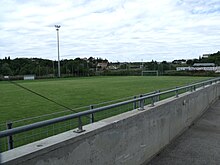 Vue du stade depuis la tribune, sous un ciel nuageux.