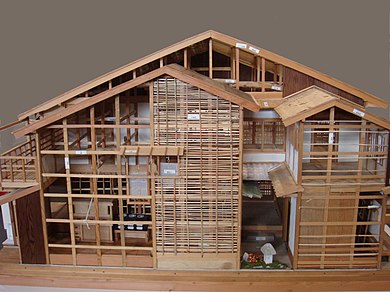 A model of a wood-frame house, with a 2-story-deep light well, surrounded by overlapping small skillion rooves at heights near the top of the ground floor, such that it has two layers of eaves.