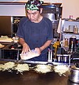 A man preparing okonomiyaki ("Hiroshima pizza")