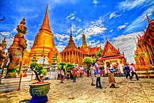 A Thai temple complex with several ornate buildings and a stupa, and a lot of visitors