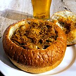 Bigos (hunter's stew) served in a bread bowl with a glass of beer at a restaurant in Kraków