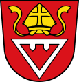 Gemeinde Wehringen In Rot ein auf die Spitze gestellter silberner Triangel, an dessen Querbalken unten zwei eggenartige Zähne angebracht sind, darüber eine goldene Mitra.