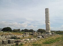 A free standing column and ruins around