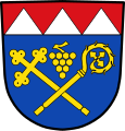 Gemeinde Kolitzheim Unter rotem Schildhaupt, darin drei gesenkte silberne Spitzen, in Blau schräg gekreuzt ein goldener Kreuzstab und ein goldener Abtstab, darüber eine goldene Weintraube.