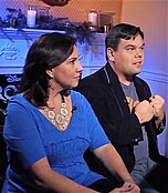 Kristen and Bobby Lopez during an interview, seen from the side