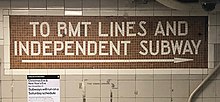Bahnhofswand mit gefliestem Mosaik mit der Inschrift „To BMT Lines and Independent Subway“ und einem Richtungspfeil.