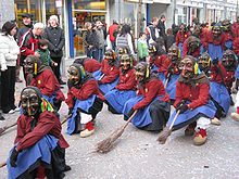 photo montrant des personnes déguisées en sorcières avec masques et balais défilant dans les rues