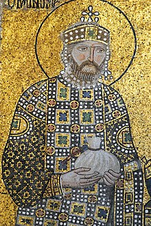 A mosaic with a background of gold showing a bearded man wearing a crown and jeweled robes holding a small bag in his hands which is tied at the top