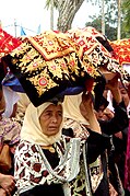 Mulheres Minangkabau carregando pratos de comida para uma cerimônia tradicional