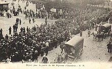 Photo noir et blanc d'une colonne de soldats en marche, entourés par des civils.