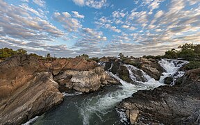 Cascades de Li Phi (chutes de Khone) au lever du soleil avec des nuages blancs et gris.