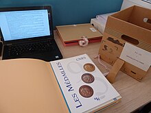 Documents d'archives du CNRS : les dossiers d'archives, un document en cours d'analyse et un ordinateur pour saisir les résultats.