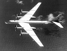 photo noir et blanc d'un avion quadrimoteur en vol au dessus de la mer.