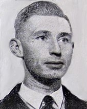 Photographie du visage d'un homme portant un costume et une cravate.