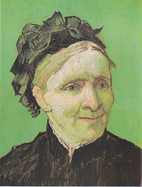 A closeup portrait of an elderly well-dressed woman sits facing to her left (the viewer's right). She has a pleasant smile and she is dressed in a dark top and she is wearing a hat, in front of a vivid green background.