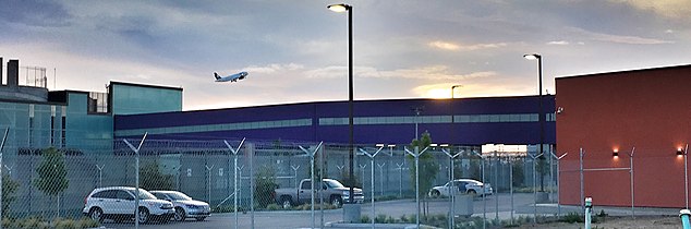 View of Cross Border Xpress (CBX) bridge from parking lot on U.S. side, with Tijuana Airport on the left and the CBX U.S. terminal on the right