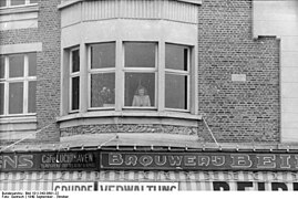 Bundesarchiv Bild 101I-343-0691-22, Belgien, Frau am Fenster über Geschäften.jpg