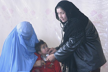 Afghani nurse treating a child with a woman wearing burqa