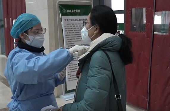 Una infermera pren la temperatura a una pacient a l'Hospital TCM de Hubei