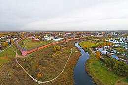 Vue aérienne d'une fortification avec des églises à l'intérieur et une petite ville autour.