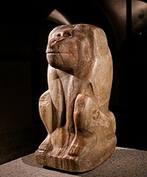 Estátua de alabastro de uma divindade em forma de babuíno com o nome do faraó Narmer inscrito na base, em exibição no on display at the Museu Egípcio de Berlim.