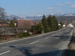 Střední část obce se silnicí č. 11 a hřebenem Hrubého Jeseníku v pozadí