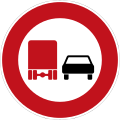 rundes Schild mit rotem Rand, im Innern links ein roter Lastwagen, rechts daneben ein schwarzes Auto (beide von hinten)