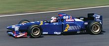 Photo d'une monoplace de Formule 1 bleue sur un circuit, vue de profil gauche.