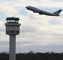 A plane taking off, with a control tower in the foreground