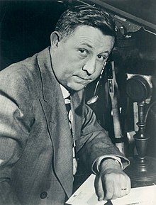 A man in a suit sitting next to a microphone
