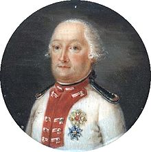 Middle aged man, plump, wearing formal tie and white jacket, with military decorations.