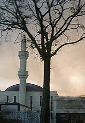 Bâtiment aux murs blancs, le minaret cylindrique présente trois segments.