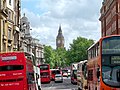 Double-decker buses frame a busy Whitehall wi Big Ben in the backgrund.