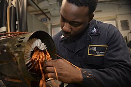 Electrician's Mate 3rd Class Eric Anderson rewiring the coils of a motor.jpg