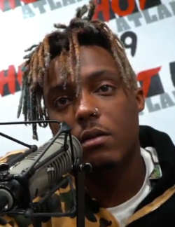 A photograph of Juice Wrld talking into a microphone during an interview