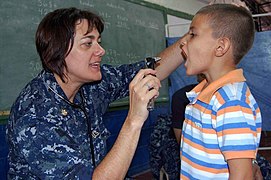 US Navy 090628-F-7885G-125 Lt. Cmdr. Kelly Hamon, embarked aboard the Military Sealift Command hospital ship USNS Comfort (T-AH 20), examines a young boy during a Continuing Promise 2009 medical community service project.jpg