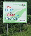 Hinweisschild Die Welt zu Gast bei Freunden™ an der A63 bei Udenheim