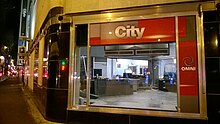 A studio partially disassembled, seen through the large picture window on the corner of the Hudson's Bay Building. City and Omni signage is seen near the window.