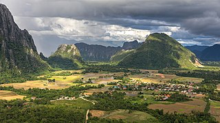 Karst peaks and green paddy fields under a stormy sky, South view from Mount Nam Xay, Vang Vieng, Laos.jpg