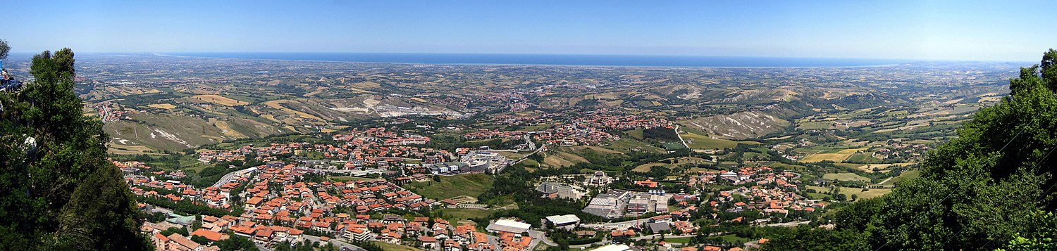 Panorama vido super la urbo San-Marino en la direkto de la Maro Adriático (NO) super la regionoj San Marino kaj Romagna (Italio). Sur la marbordo videblas la areo inter Cervia kaj almenaŭ Gabicce Mare, kun Cesenatico, Rimini videblas inter la du. En la antaŭa plano, la sanmarinaj komunumoj Borgo Maggiore, Valdragone, Cailungo, Domagnano, Serravalle kaj aliaj.