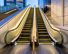 Front view of an illuminated outdoor escalator, Shinjuku Station, Tokyo.jpg