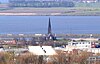 A distant view of a stone church with a tall steeple